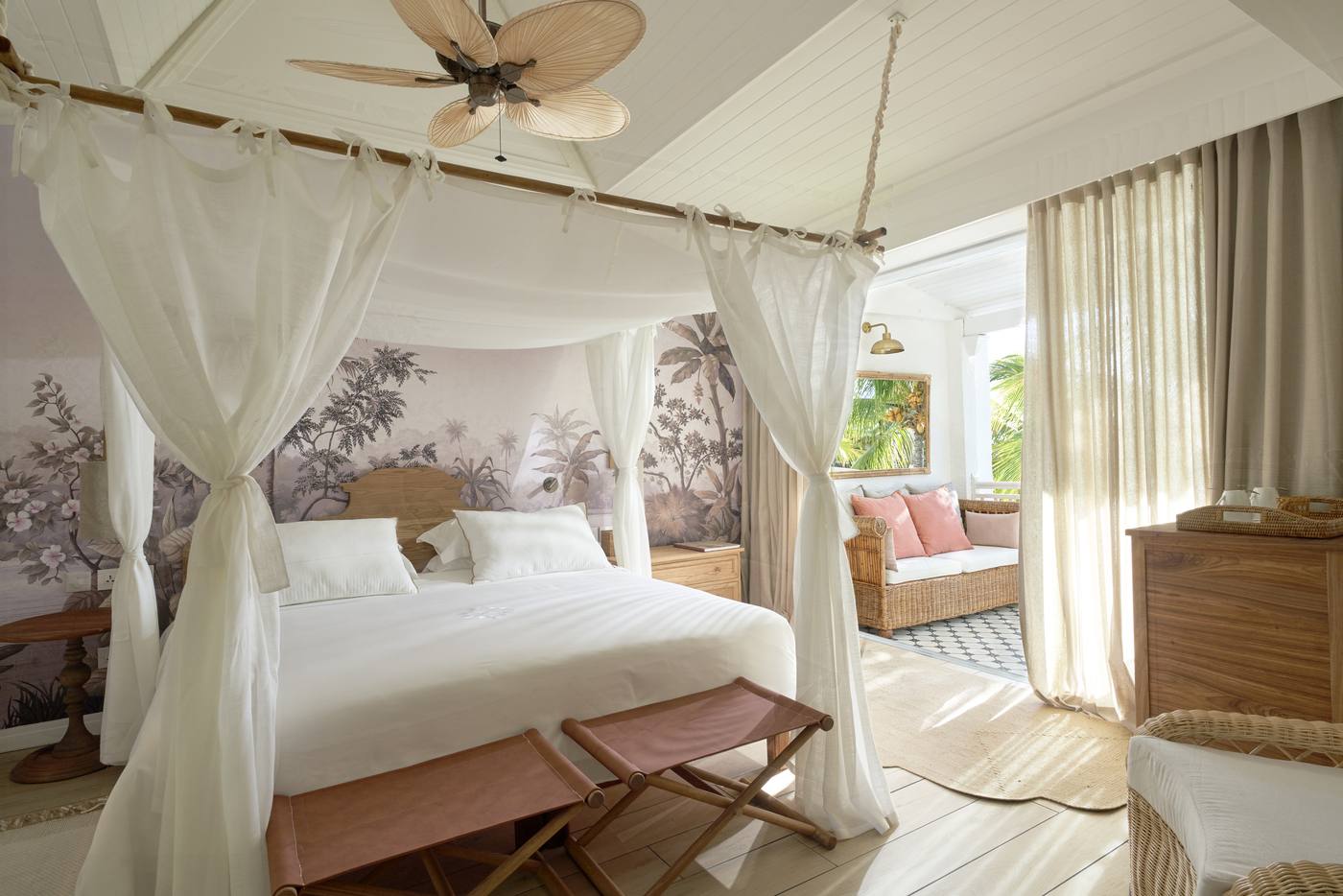Chambre à lit à baldaquin, ouverte sur une terrasse et des cocotiers