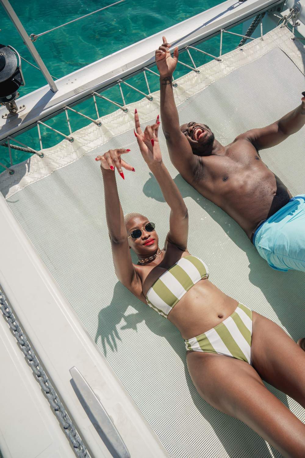 Un couple détendu sur le filet du catamaran, au-dessus d'une eau turquoise